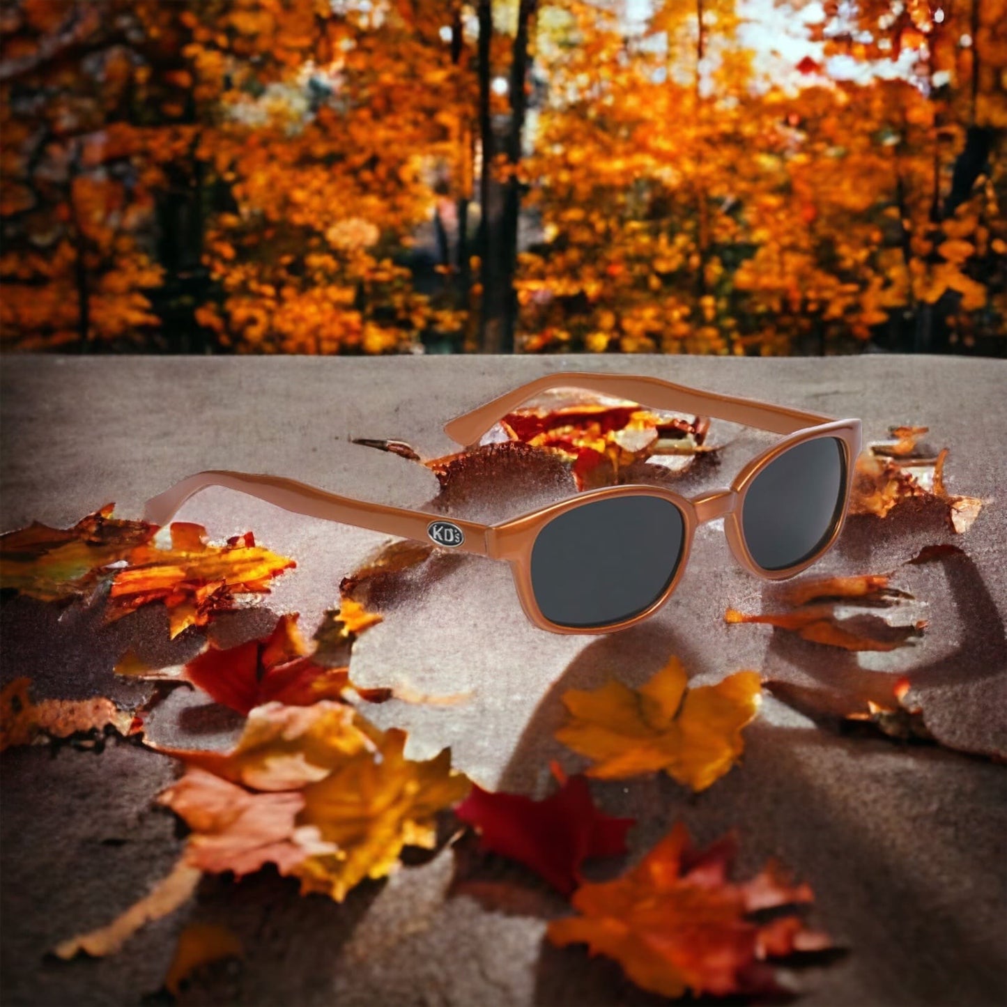 KD's 20128 sunglasses that fit under a motorcycle or ski helmet. For bikers and sportsmen. With a rugged orange metallic frame and dark gray tinted lenses. In an autumn forest with orange leaves.