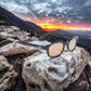 KD's 20114 sunglasses that fit under a motorcycle or ski helmet. With a classic black frame and clear colored mirror lenses set on a rock in front of a sunset.