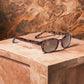 X-KD's 100 sunglasses with amber lenses and a frame with turtle shell motifs placed on a marble countertop