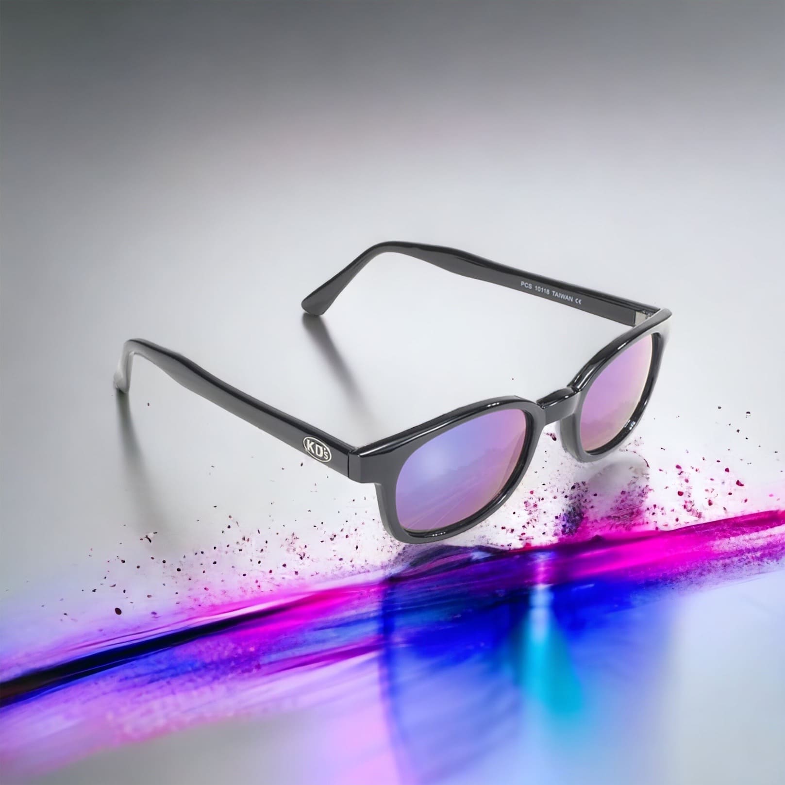 X-KD's 10118 large sunglasses for sportsmen and bikers with a stylish black frame and iridescent polycarbonate mirror lenses in front of a paint chip.