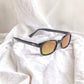 X-KD's 11119 large sunglasses for sportsmen with a stylish black frame and durable amber polycarbonate lenses set on white sheets.