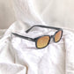 X-KD's 11119 large sunglasses for sportsmen with a stylish black frame and durable amber polycarbonate lenses set on white sheets.