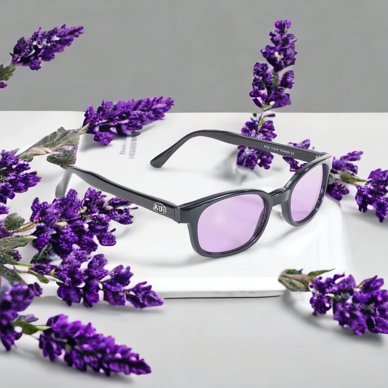 Large X-KD's 11216 sunglasses worn by Jax Teller and the Sons of Anarchy bikers with a sublime black frame and durable purple polycarbonate lenses set on a towel surrounded by lavender.