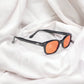 X-KD's 1128 sunglasses with orange lenses and a charming black frame placed on white sheets