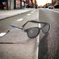 The X-KD's 1227 sunglasses with grey lenses and a motorcycle tailpipe decor mounted on the road in the street.
